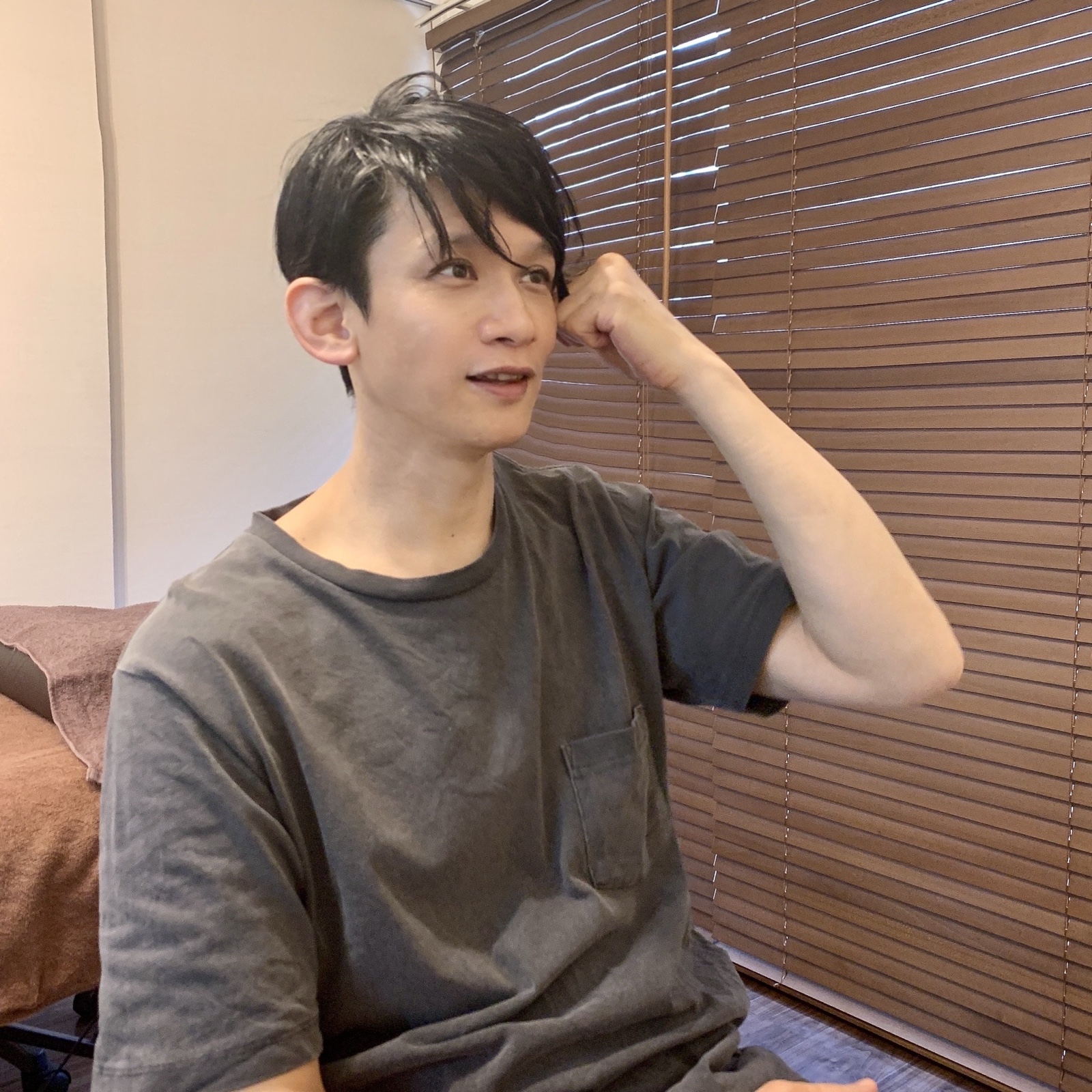 ムーンテッド(MoonTed)の日記より、髪に手をやり、横を向いて笑うムーンテッド(MoonTed)のセラピストAKI。グレーのTシャツ姿