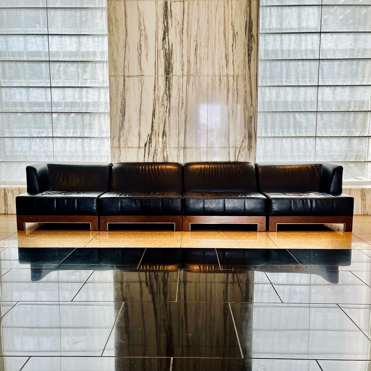MoonTed Diary: A long black leather sofa in front of a marble pillar in the hotel lobby, reflected in the polished floor