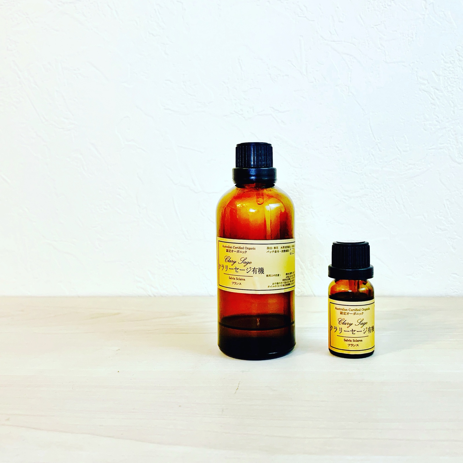 MoonTed Diary: Two amber bottles of certified organic clary sage essential oil, one large and one small, against a white wall