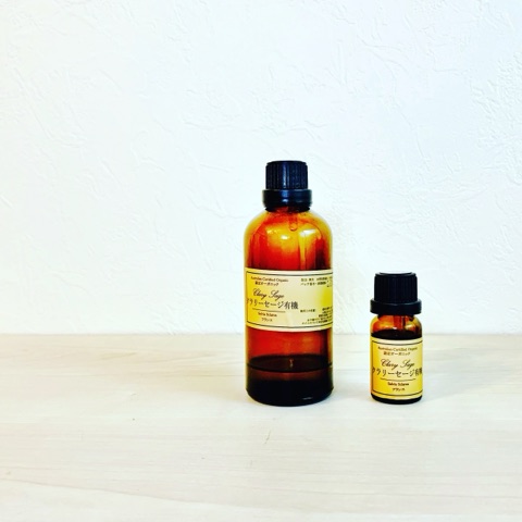 MoonTed Diary: Two amber bottles of certified organic clary sage essential oil, one large and one small, against a white wall