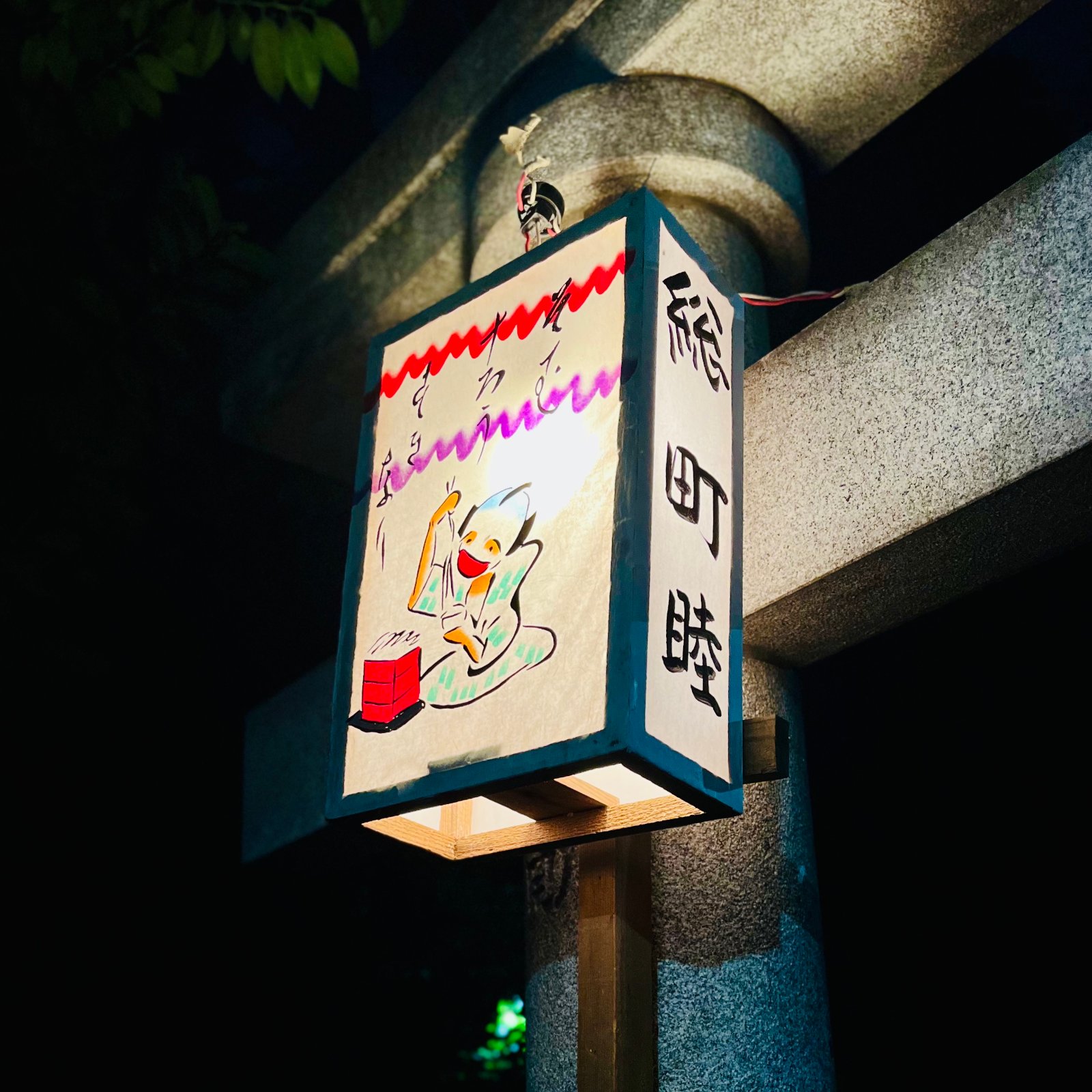 ムーンテッド（MoonTed）の日記より、代々木八幡宮の例大祭で灯る「総町睦」の提灯。町人の男がせいろから蕎麦を食べる絵が手描きされている。
