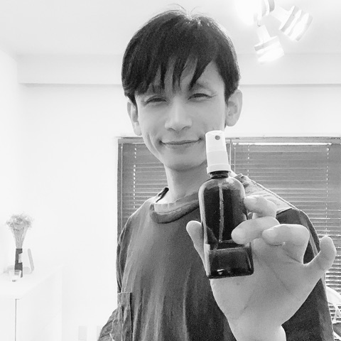 MoonTed Diary: Therapist AKI smiling and holding out a small spray bottle toward the camera, in black and white