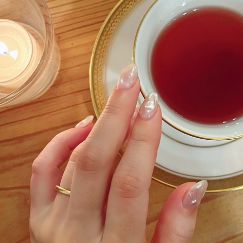 MoonTed Diary: A guest's hand with pale pink pearly nails on her wedding day, beside a gold-rimmed cup of tea and a candle