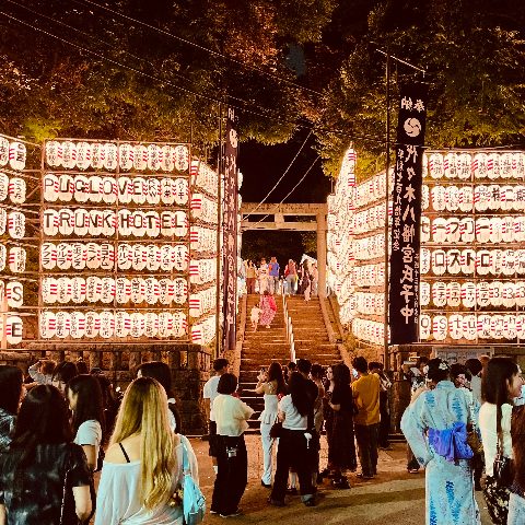 ムーンテッド（MoonTed）の日記より、夜の代々木八幡宮の例大祭。奉納提灯がずらりと並ぶ参道の階段を、浴衣姿の人たちが上っていく。