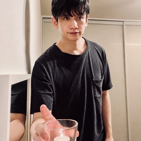 ムーンテッド（MoonTed）の日記より、セラピストのAKI。黒いTシャツ姿で、火を灯したキャンドルをグラスごと差し出すように持っている。左手には鏡に映った自分の姿。