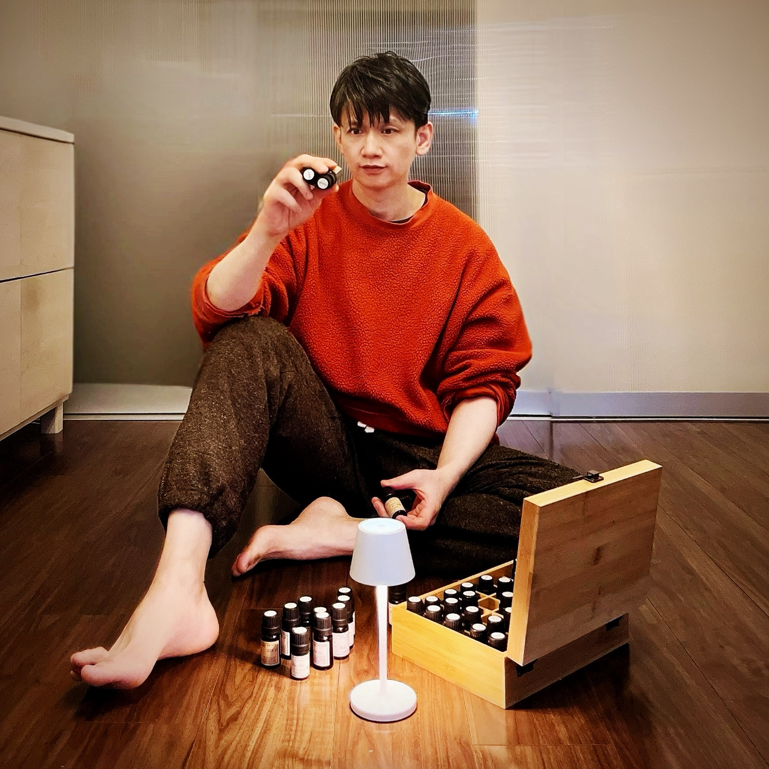 MoonTed Diary: Therapist AKI holding up a small essential oil bottle, wearing an orange sweater