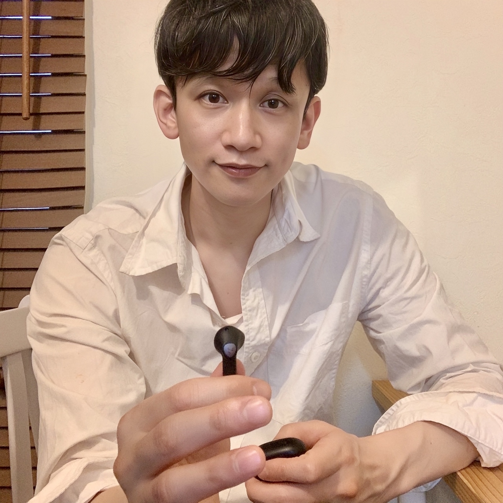 ムーンテッド(MoonTed)の日記より、ワイヤレスイヤホンを手に、こちらを見るムーンテッド(MoonTed)のセラピストAKI。白いシャツ姿