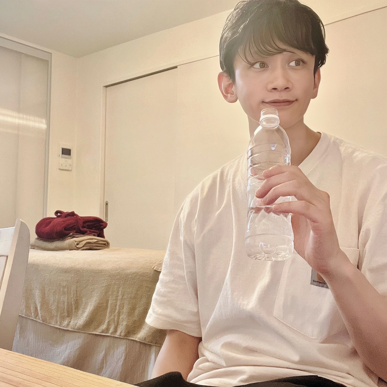 ムーンテッド（MoonTed）の日記より、ペットボトルの水を手に、横を見て微笑むムーンテッド（MoonTed）のセラピストAKI。奥に施術台