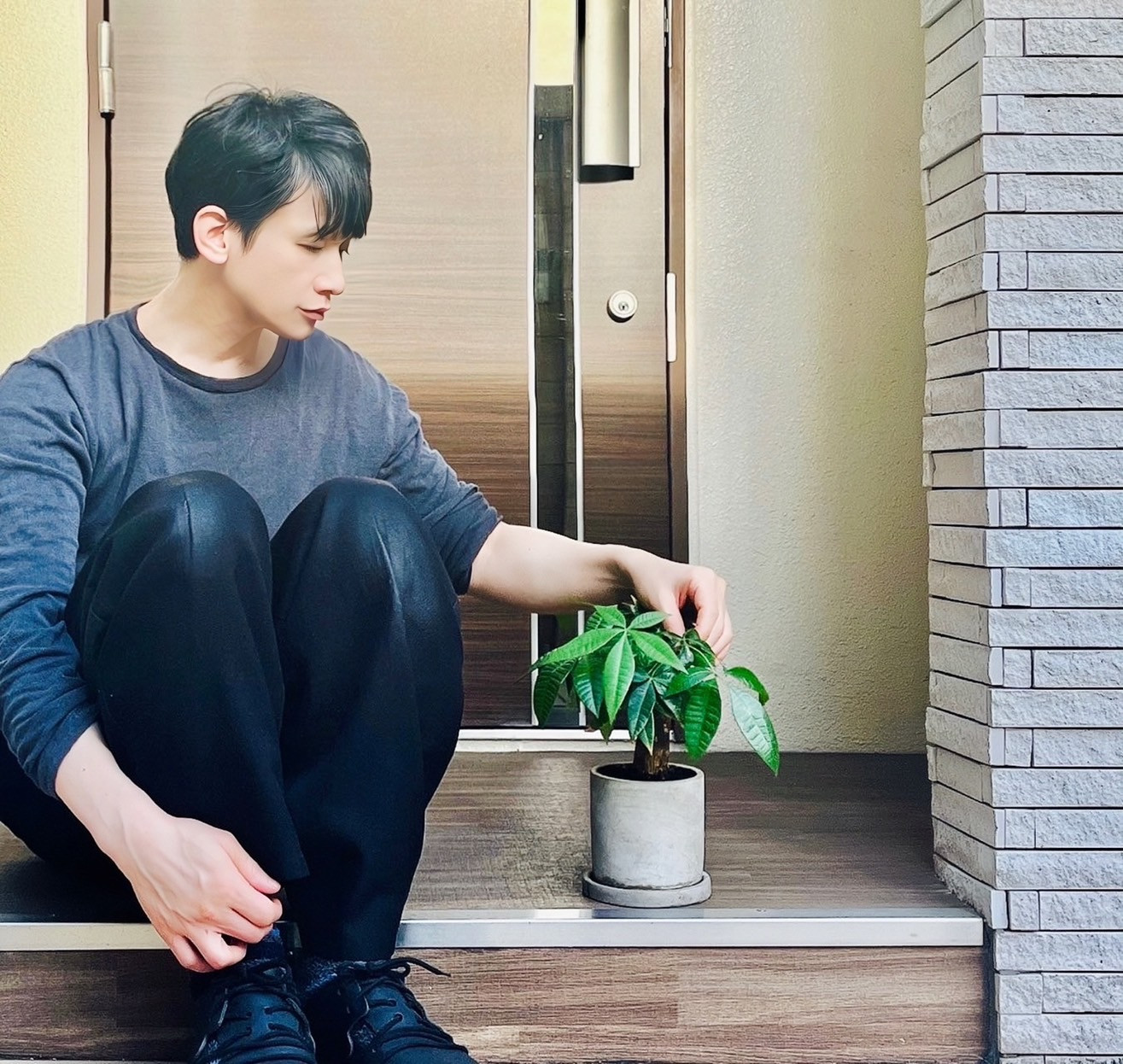ムーンテッド(MoonTed)の日記より、玄関先に座り、パキラの葉に触れるムーンテッド(MoonTed)のセラピストAKI