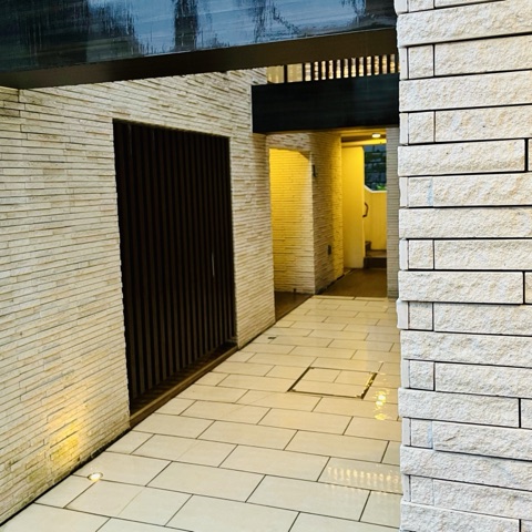 ムーンテッド（MoonTed）の日記より、雨に濡れたマンションの通路。石張りの壁と、足元に灯るライト