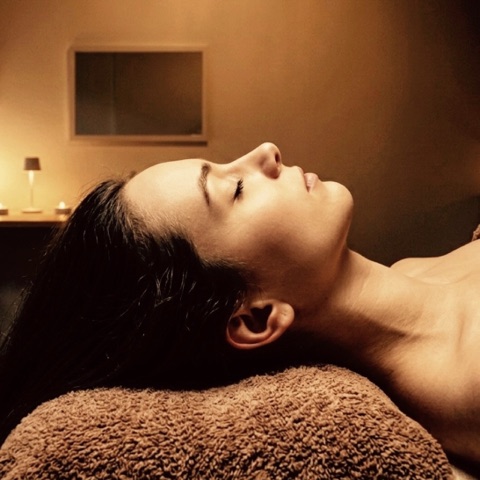 MoonTed Diary: Side profile of a woman with her eyes closed, resting her head on a brown towel in warm light