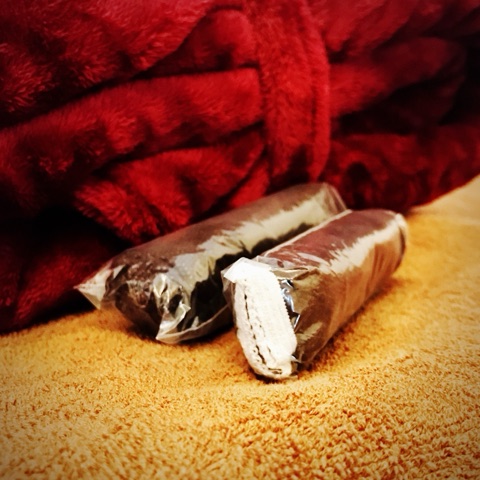 ムーンテッド（MoonTed）の日記より、個包装された使い捨ての紙ショーツ2つ。茶色のタオルの上、奥に赤いガウン